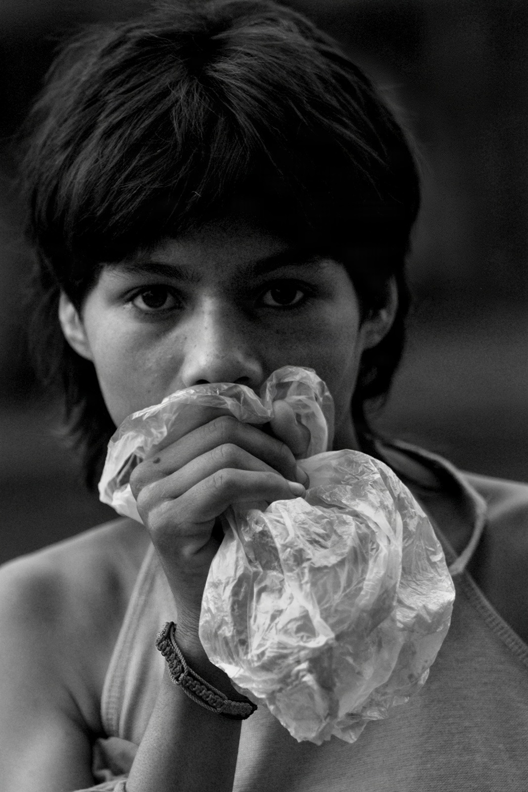 A teenage girl breaths glue fumes from a bag October 15, 2003 in Tegucigalpa, Honduras. A common problem in Central America, homeless children often use glue to get high and to take away hunger pains.