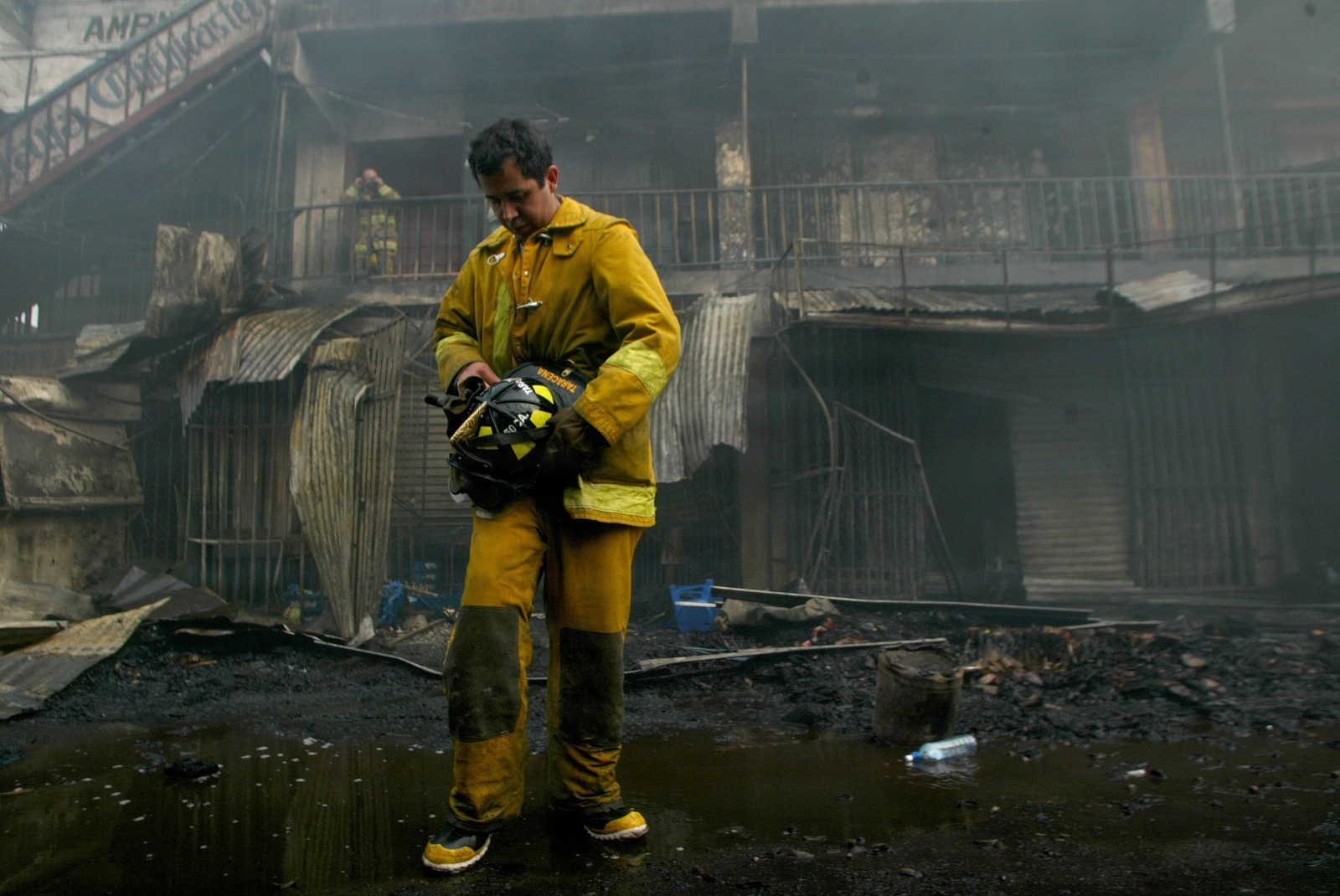 A Firefighter takes a breather after battling a fire that raged through a local market November 20, 2006 in Guatemala City. Fifteen people died after one of Guatemala City's largest central market's caught fire Monday, suffocating people trapped inside the labyrinthine building of basic grain and vegetable stalls. REUTERS/Daniel LeClair   (GUATEMALA)