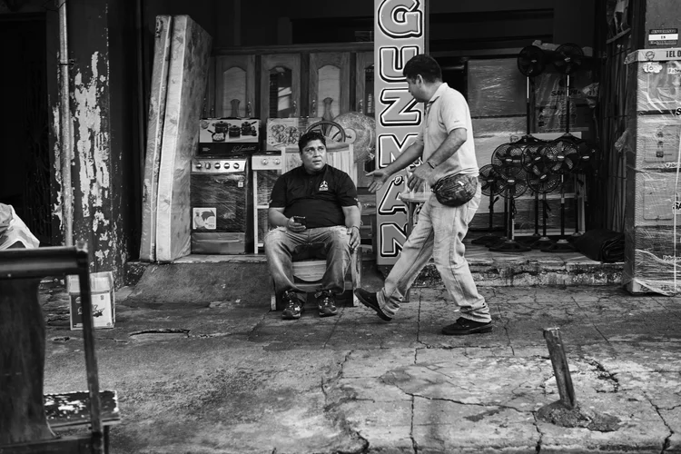 Two men outside a store with appliances and fans on display.