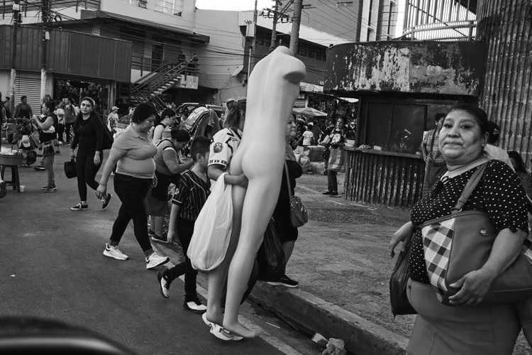 Street scene with people walking and carrying a mannequin.