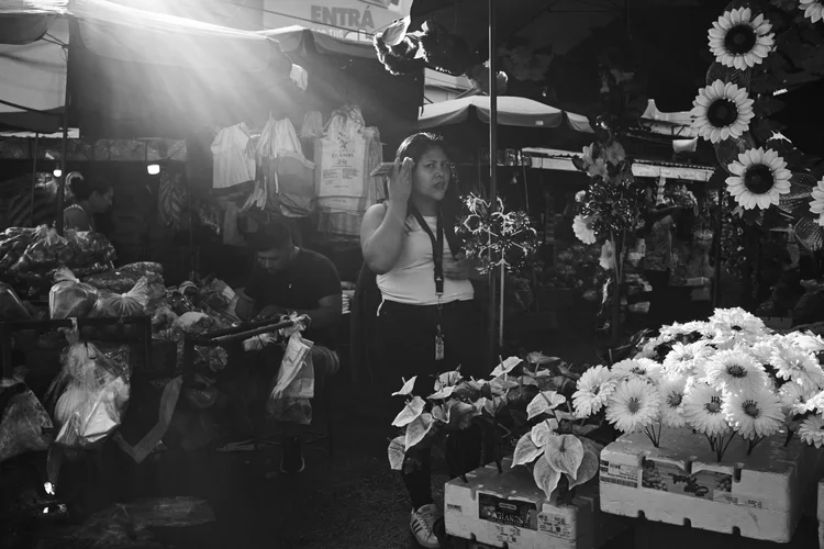 Black and white photo of a market scene with flowers and people shopping
