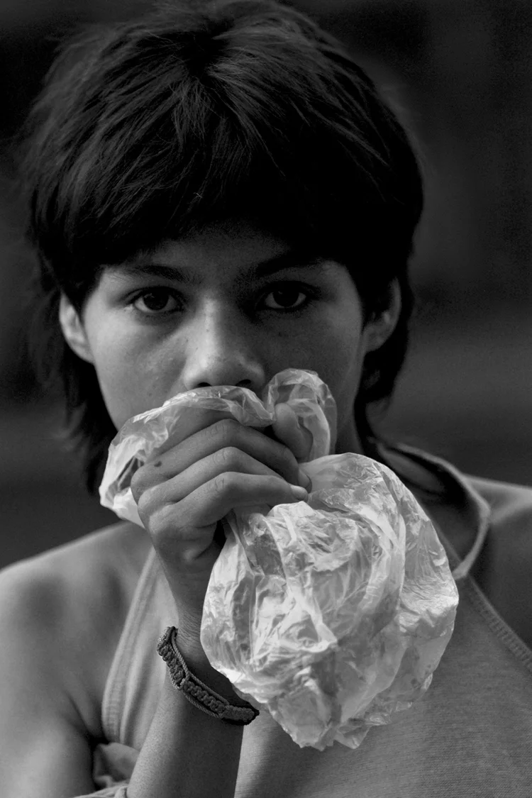 Black and white photo of a person holding a plastic bag to their face.