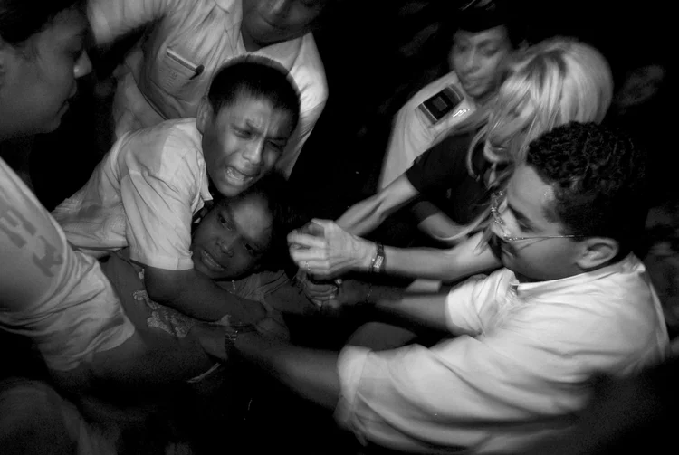 Black and white image of people in a struggle, showing a mix of emotions and physical confrontation.