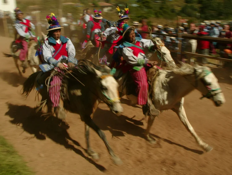 A group of horsemen wearing colorful traditional costumes riding fast in a cultural festival.