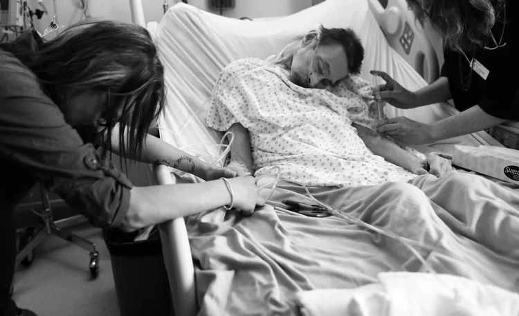 PJ McGrath's daughter comforts her dad as Dr. H administers medication during his assisted death in his hospital room.